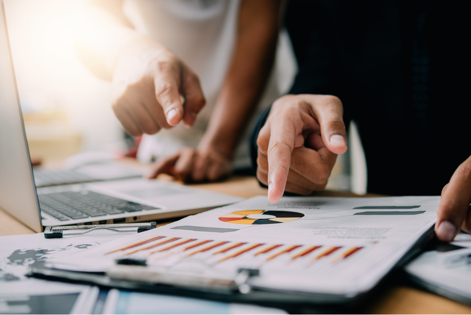 Two people analyzing and pointing at a document with charts